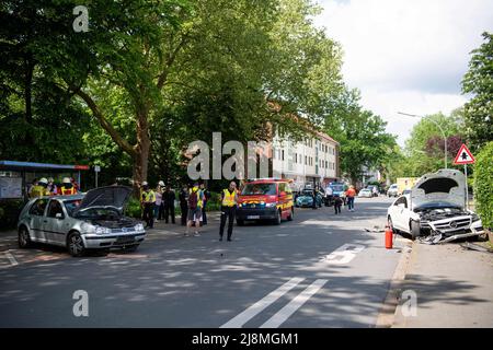 Delmenhorst, Deutschland. 17.. Mai 2022. Feuerwehrleute sind am Unfallort im Einsatz, zwei beschädigte Autos stehen vor einer Bushaltestelle und am Straßenrand. Bei einem Verkehrsunfall mit zwei Autos vor einer Berufsschule in Delmenhorst wurden mehrere Personen, zum Teil schwer verletzt. Quelle: Melissa Erichsen/dpa/Alamy Live News Stockfoto