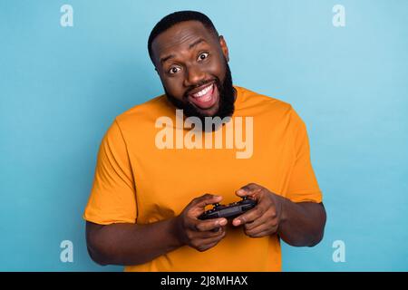 Portrait von attraktiven fröhlich lustig bärtigen Kerl spielen Netzwerk-Spiel Spaß isoliert über hellen blauen Hintergrund Stockfoto