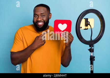 Portrait von stattlichen Kerl Aufnahme Video Demonstration Herzkarte smm post media isoliert über hellen blauen Hintergrund Stockfoto