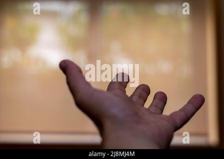 Bitten oder Betteln um Hilfe mit offener Hand zu einem Fenster oder Fensterlicht. Leiden im Schweigen, häusliche Gewalt oder stille Gewalt. Um Hilfe bitten, um zu entkommen. Stockfoto