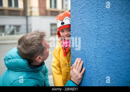 Vater bringt seine kleine Tochter mit Down-Syndrom zur Schule, draußen auf der Straße. Stockfoto