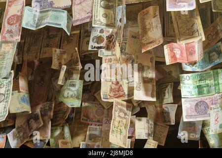 Viele alte Banknoten aus verschiedenen Ländern hängen an der Decke des Pubs Stockfoto