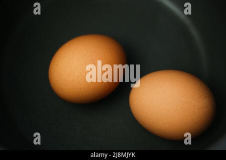 Zwei braune Eier in einem Topf mit Wasser auf dem Herd Stockfoto