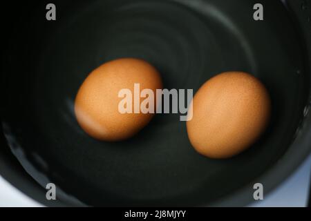 Zwei braune Eier in einem Topf mit Wasser auf dem Herd Stockfoto