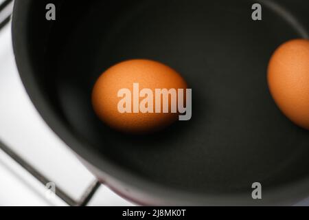 Zwei braune Eier in einem Topf mit Wasser auf dem Herd Stockfoto