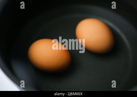 Zwei braune Eier in einem Topf mit Wasser auf dem Herd Stockfoto