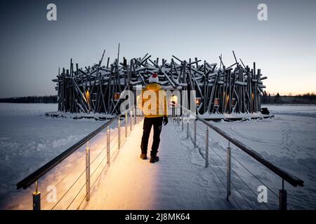 Person, die das runde Hauptgebäude des Arctic Bath Hotel aus Holz aus gefrorenem Gehweg bewundert, Harads, Lappland, Schweden Stockfoto