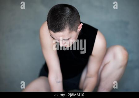 Nicht binär, sie/sie in Squat-Position Stockfoto