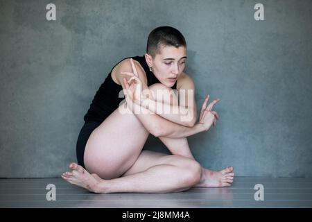 Nicht binär, sie/sie in Squat-Position Stockfoto