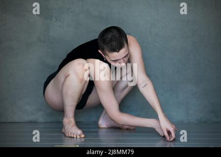 Nicht binär, sie/sie in Squat-Position Stockfoto