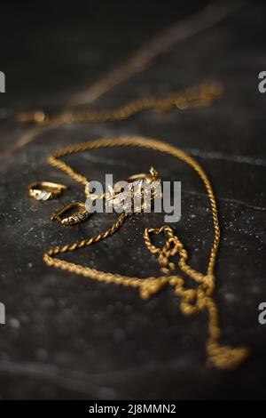 Goldring in Form eines Krokodils mit einer goldenen Kette auf dunklem Marmorboden Stockfoto