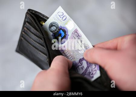 Legt Geldbörse ein oder zieht 20 britische Pfund Rechnung heraus Stockfoto