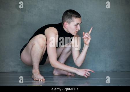 Nicht binär, sie/sie in Squat-Position Stockfoto