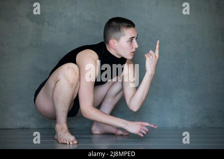 Nicht binär, sie/sie in Squat-Position Stockfoto