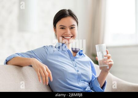 Porträt einer fröhlichen asiatischen Frau mit einem Glas Wasser Stockfoto