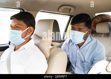 Passanger mit Taxifahrer reden über das Ziel, während beide in Maske wegen Coronavirus Pandemie - Konzept der Reise mit covid sicher Vorsichtsmaßnahmen Stockfoto