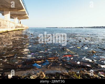 Plastikmüll auf blauer Meeresoberfläche. Verschmutzter Strand. Müll, Flaschen und andere Plastikmüll im Meerwasser. Stockfoto