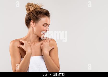 Porträt Der Schönen Kaukasischen Frau Stehend In Handtuch Über Grauem Hintergrund Gewickelt Stockfoto