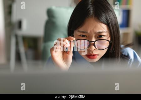 Verwirrt asiatische Dame mit Laptop Blick auf den Bildschirm Stockfoto