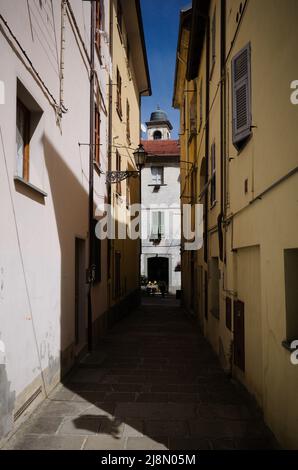 Schmale Straße in der Altstadt von Borgo Val di Taro, Provinz Parma, Italien. Enge gepflasterte Straße zwischen alten Häusern und dem Glockenturm der Stadt Stockfoto