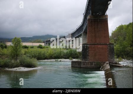 Eisenbahnbrücke über den Fluss Taro in Borgo Val di Taro, Provinz Parma, Italien. Die Eisenbahnbrücke auf den Stützen über dem Fluss in den Bergen Apennins Stockfoto