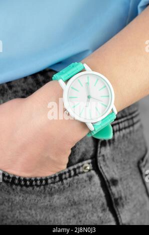 Elegante grüne Armbanduhr mit weiblicher Hand, Nahaufnahme. Frauenhand in der Jeanentasche Stockfoto