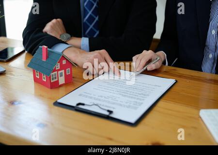 Immobilienmakler sprach über die Bedingungen des Hauskaufvertrags und bat den Kunden, die Dokumente zu unterzeichnen, um den Vertrag legal zu machen Stockfoto
