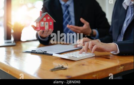 Immobilienmakler sprach über die Bedingungen des Hauskaufvertrags und bat den Kunden, die Dokumente zu unterzeichnen, um den Vertrag legal zu machen Stockfoto