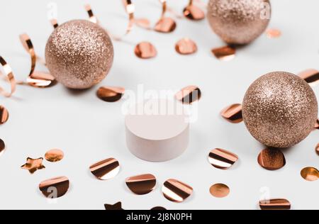 Podium mit Neujahrsdekor, roten Kugeln, Konfetti und Girlande-Lampen. Beigefarbener Sockel für Produktdemonstration auf weißem festlichem Hintergrund. Chris Stockfoto