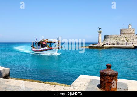 Eine Gruppe von Touristen, die auf einer Reise vor Ort sind, an Bord eines kleinen Bootes, das zum Hafen von Mandhraki in der historischen Stadt Rhodos, Rhodos, Griechenland, zurückkehrt Stockfoto