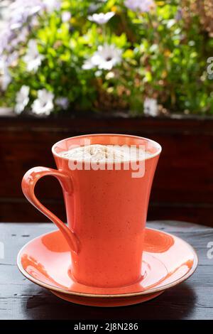 Eine frisch gebrühte Tasse Espresso Kaffee auf einem Kaffeetisch im Freien der Kaffee wird in einem hellen Becher und einer Untertasse serviert und hat eine cremige, dicke Crema Stockfoto