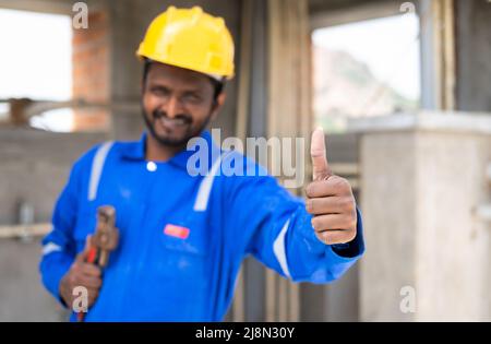 Klempner mit Rohr und Sanitär-Werkzeug in der Hand zeigt Daumen durch Blick auf Kamera - Konzept des Servicemannes bereit zu arbeiten, Vertrauen und Profi Stockfoto