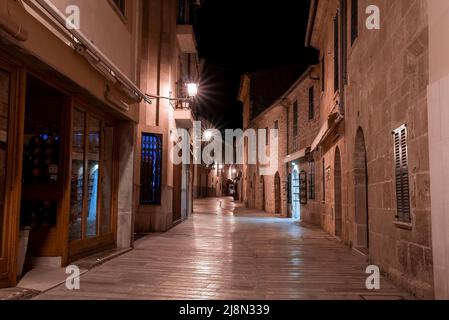 Beleuchtete Gasse inmitten von Wohngebäuden in der Altstadt bei Nacht Stockfoto