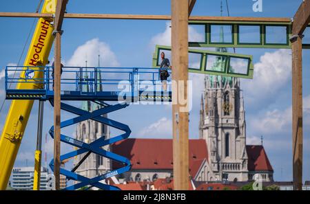 München, Deutschland. 17.. Mai 2022. Auf dem Oktoberfestgelände stellen Arbeiter das erste Bierzelt seit dem Ausbruch der Corona-Pandemie zusammen, im Hintergrund die St. Pauls-Kirche. Das Zelt ist eine komplett neue Konstruktion. Das Oktoberfest findet in diesem Jahr vom 17. September bis zum 3. Oktober 2022 statt. Kredit: Peter Kneffel/dpa/Alamy Live Nachrichten Stockfoto