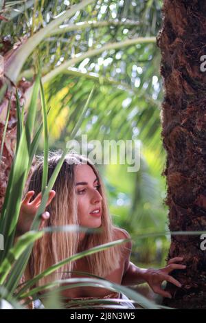 Wunderschöne junge Frau, die sich im tropischen Dschungel, umgeben von Natur und Vegetation, mitten im Nirgendwo auf der Suche nach dem Rückweg, verirrt hat Stockfoto