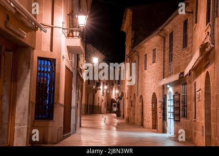 Beleuchtete leere Gasse inmitten von Gebäuden in der alten Wohnstadt bei Nacht Stockfoto