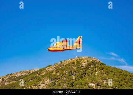 Wasserflugzeug Canadair fliegt über eine wunderschöne Klippe gegen den blauen Himmel Stockfoto