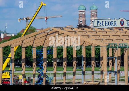 München, Deutschland. 17.. Mai 2022. Auf dem Oktoberfest bauen Arbeiter das erste Bierzelt seit dem Ausbruch der Corona-Pandemie. Im Hintergrund sind die beiden Türme der Frauenkirche zu sehen. Das Zelt ist eine komplett neue Konstruktion. Das Oktoberfest findet in diesem Jahr vom 17. September bis 3. Oktober 2022 statt. Kredit: Peter Kneffel/dpa/Alamy Live Nachrichten Stockfoto