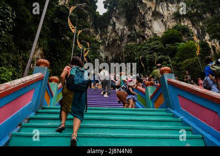 Ein Touristenmädchen, das die steilen Stufen vor den Batu-Höhlen klettert Stockfoto