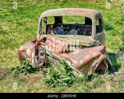Rostende Überreste eines zertrümmerten alten Autos ruhen auf einer Weide in der Nähe von Molson, Washington. Stockfoto