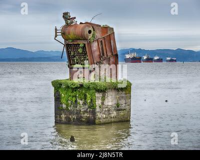 Ein kleiner Schiffskonvoi vor Anker liegt hinter einem alten Industriegerät auf dem Columbia River in der Nähe von Astoria, Oregon. Stockfoto