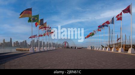 Die offizielle Countdown-Uhr der FIFA World Cup Qatar 2022 am malerischen Küstenfischerspot von Doha mit Flaggen der teilnehmenden Länder Stockfoto