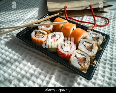 Online-Bestellung und Lieferung von Lebensmitteln. Sushi ist ein japanisches Gericht. Stockfoto