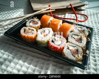 Online-Bestellung und Lieferung von Lebensmitteln. Sushi ist ein japanisches Gericht. Stockfoto