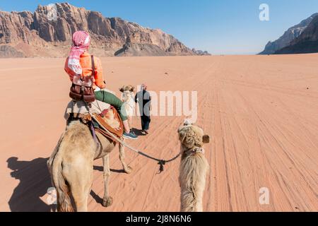 Schöne junge Frau Tourist in weißem Kleid Reiten auf Kamel in wadi Rum Wüste, Jordanien Stockfoto