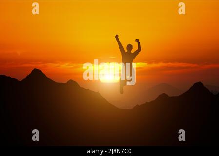 Glücklicher Mann, der auf dem Gipfel des Berges mit abstraktem Hintergrund am Himmel bei Sonnenuntergang springt. Freiheit wohlfühlen und Sommerurlaubskonzept. Vintage-Ton-Filtereffekt Stockfoto