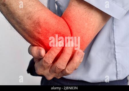 Schmerzen im Ellenbogengelenk des südostasiatischen älteren Mannes. Konzept von Ellenbogenschmerzen, rheumatoider Arthritis und Armproblemen. Stockfoto