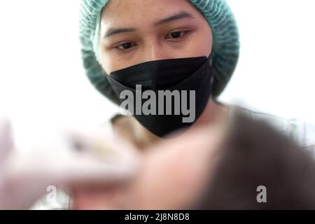 Porträt einer Krankenschwester, die auf einen Patienten schaut, der eine Schönheitsbehandlung erhält Stockfoto