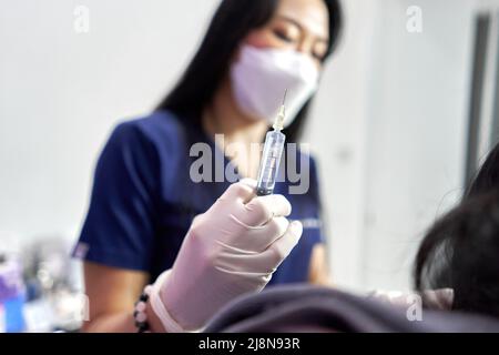 Konzentrieren Sie sich auf die Hand eines Arztes, der eine Botox-Injektion für einen Patienten hält Stockfoto