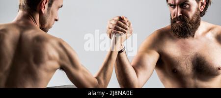 Zwei Männerhände umspannten Arm Wrestling, stark und schwach, ungleich. Armdrücken. Stark muskulös bärtiger Mann, der einen schwach schwachen Mann am Arm kämpft. Arme Stockfoto